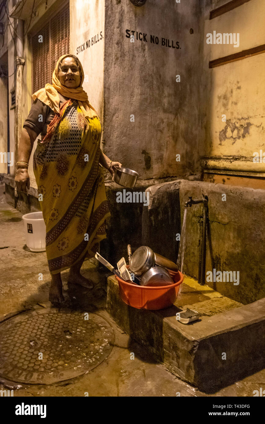Vertical portrait of a poor lady doing her washing up at a standpipe in Kolkata aka Calcutta, India. Stock Photo