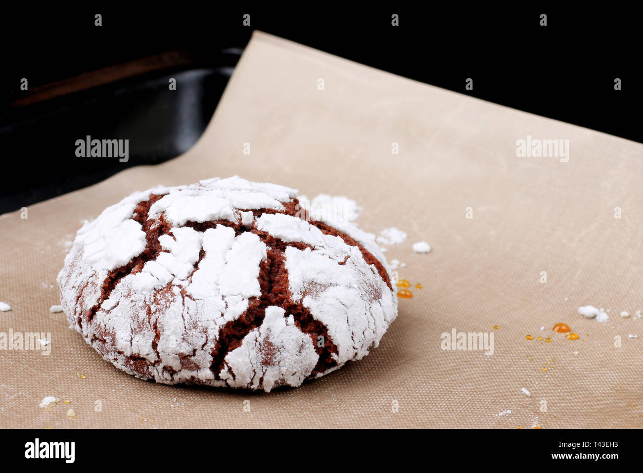 Chocolate cookies with cracks on baking paper and iolated on black. Cracked chocolate biscuits. Stock Photo