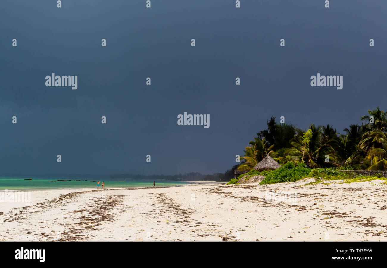 tropical beach with silhouetes of unrecognizable people in the distance Stock Photo