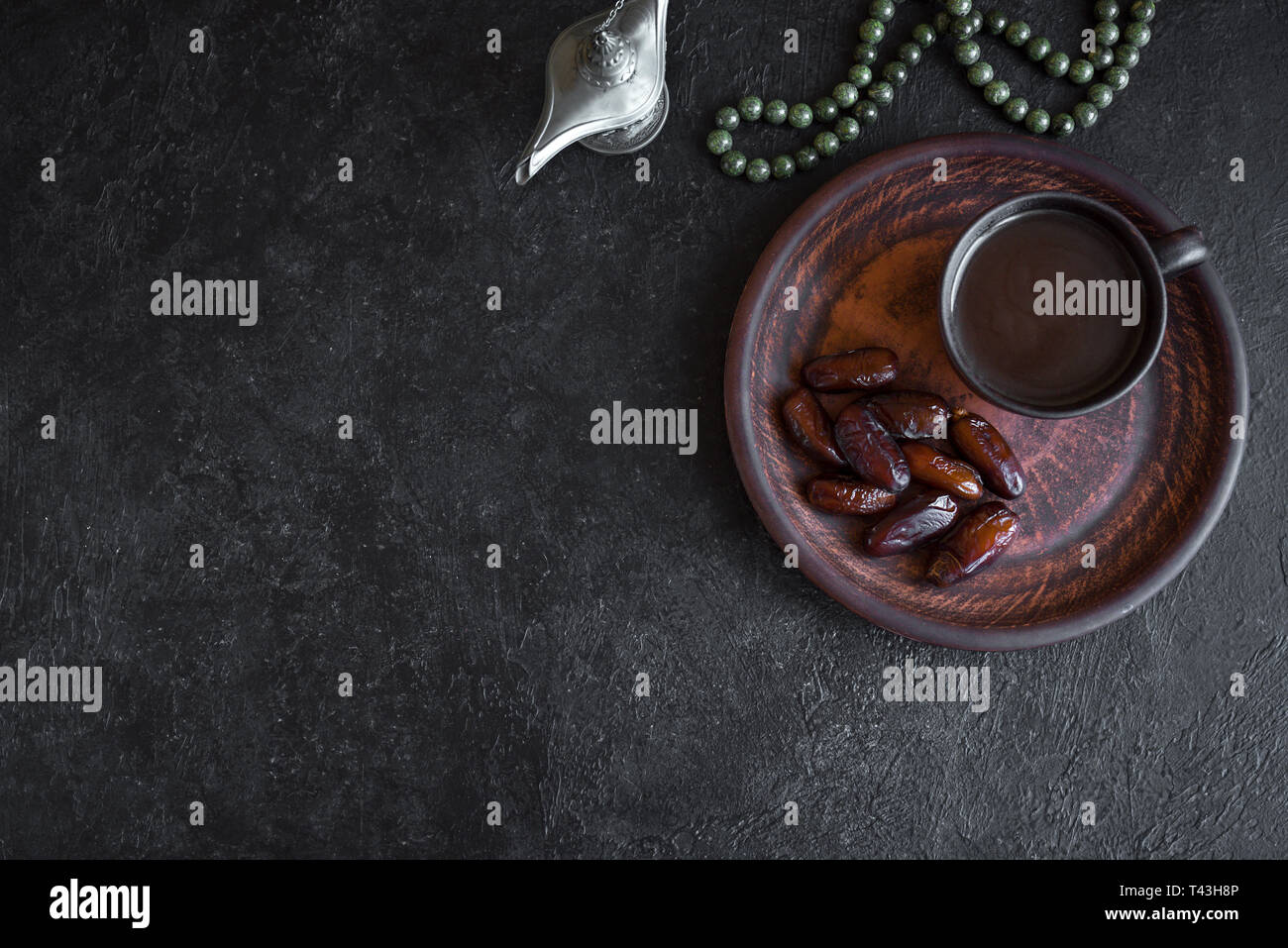 Traditional Muslim Iftar Food on black, copy space. Ramadan kareem with premium dates and coffee. Ramadan iftar food concept with rosary. Stock Photo