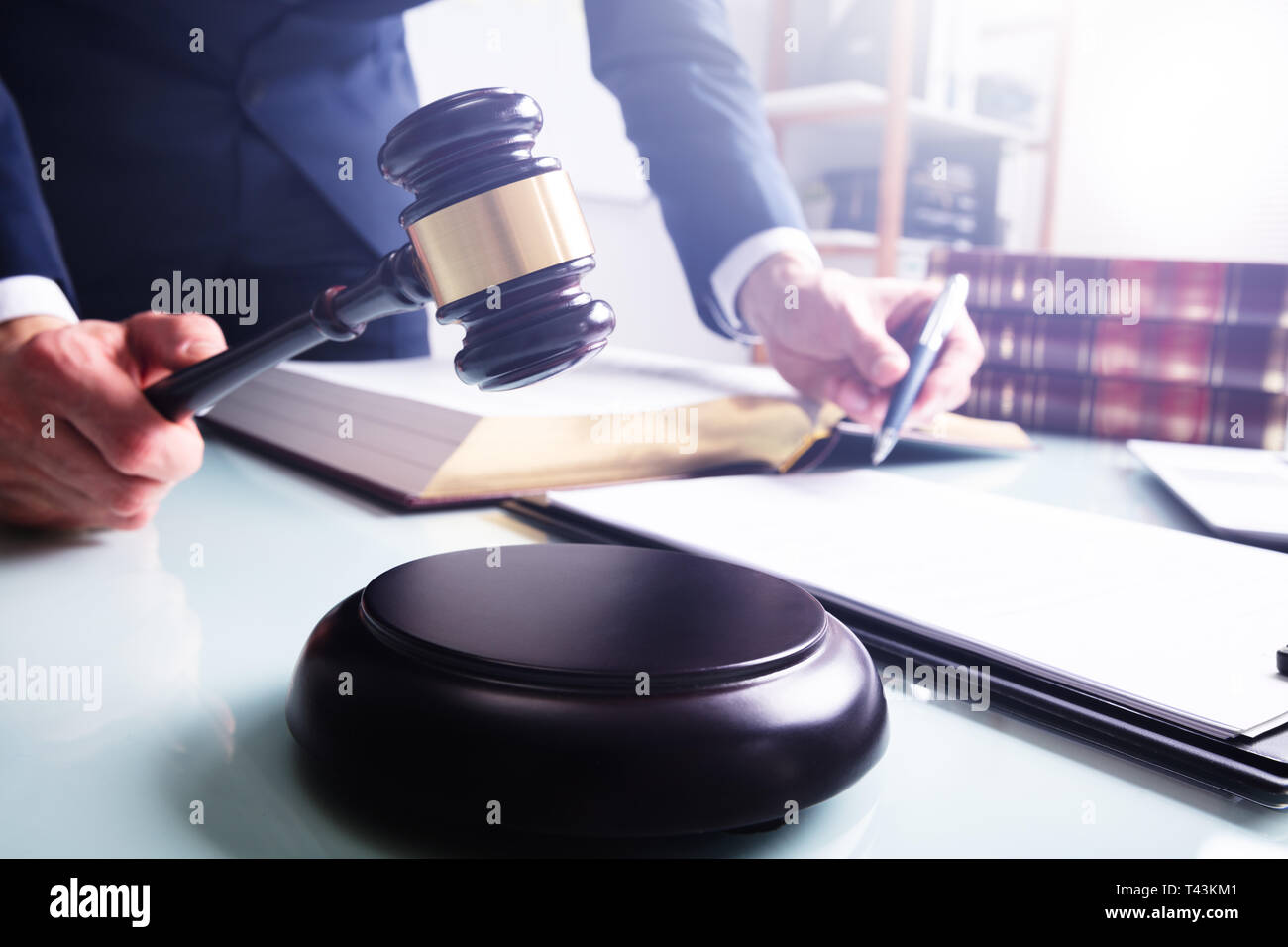 Midsection Of Male Judge In Courtroom Striking Mallet On Sound Block Over Desk Stock Photo
