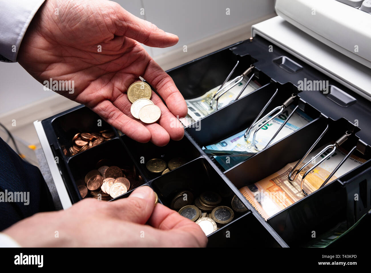 An Overhead View Of Cashier's Hand Taking Banknote From Opened Till Stock Photo