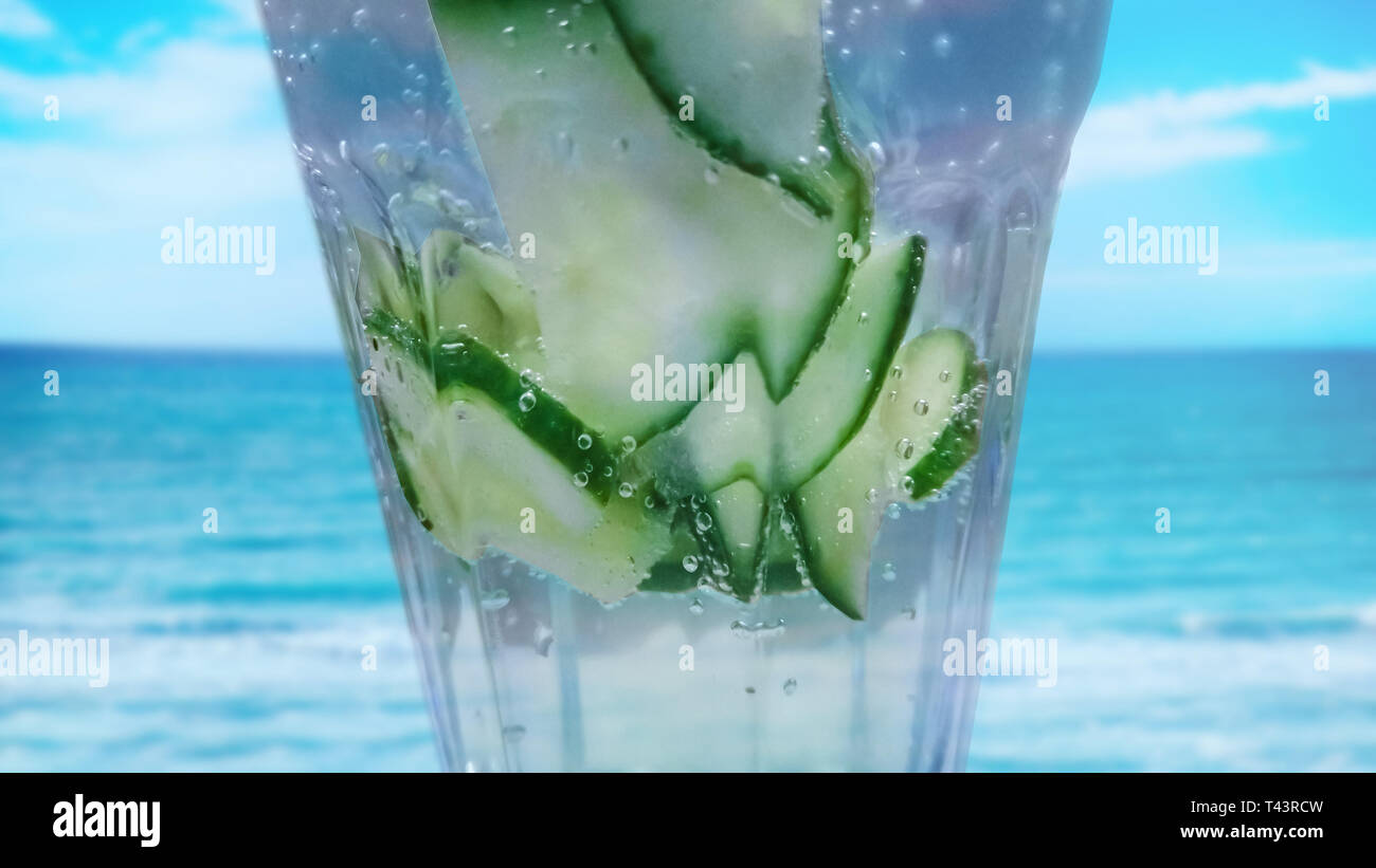 Close up of Cucumber drink cocktail with fresh water. It is home made cucumber limo. In the background is turquois water sea. It is tropical backgroun Stock Photo