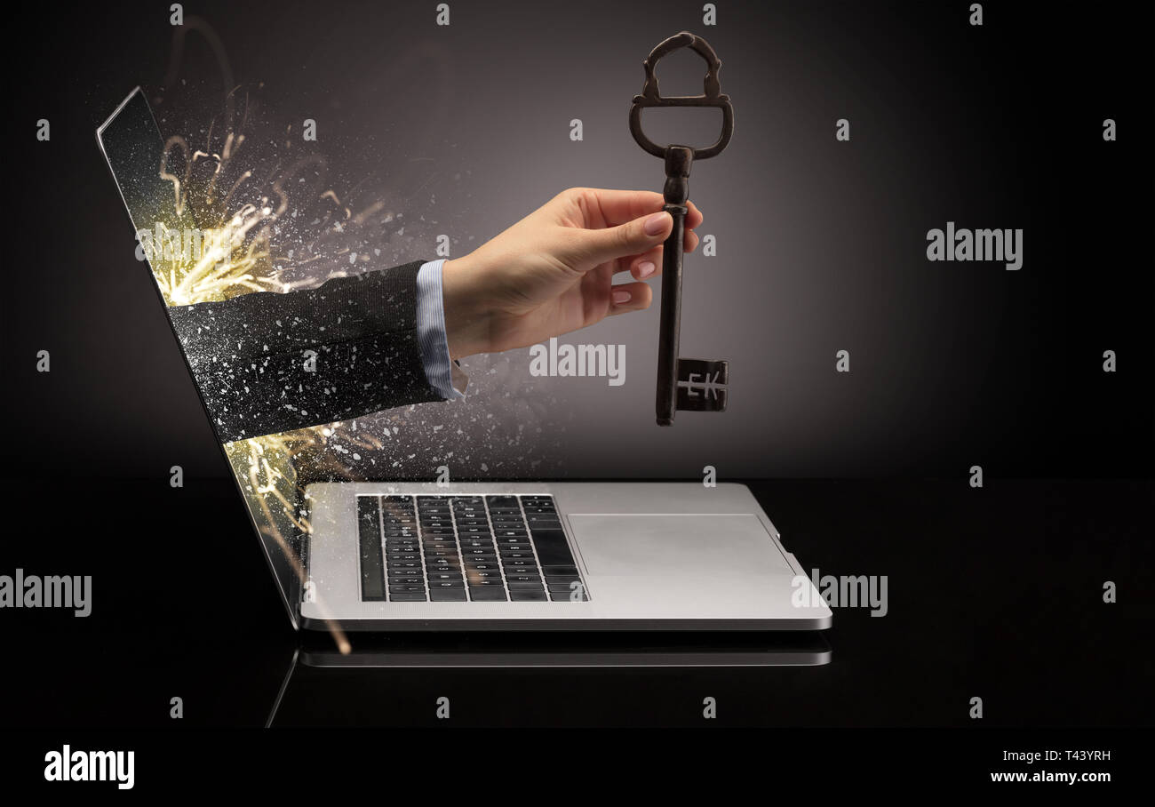 Hand with huge vintage key coming out of a laptop with sparkling