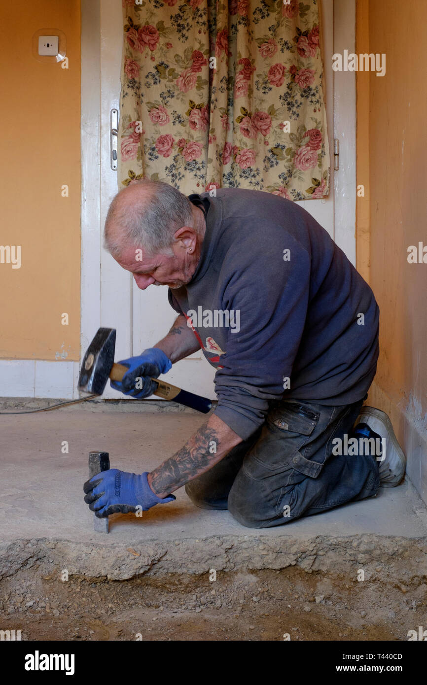 man using hammer and chisel to dig up concrete floor during house renovations zala county hungary Stock Photo