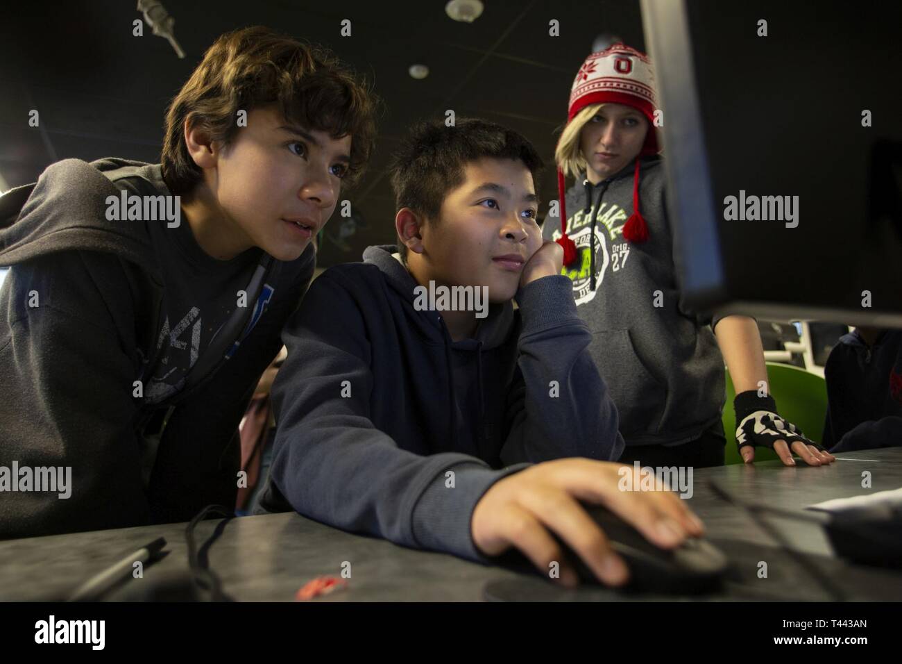 Sixth graders Logan Tjahjadi Crawford, 12, of Anaheim, left, and Timothy Louie, 11, of Fullerton, center, along with seventh grader Emily Rodeghiero, 13, of La Habra, right, evaluate performance changes to their rocket design using computer simulation software in the computer aided design lab March 13, 2019, at STARBASE Los Alamitos at Joint Forces Training Base, Los Alamitos, California. The students are part of the STARBASE site's rocketry team which is competing in the Team America Rocketry Challenge (TARC) competition with hopes of making it to the National Fly Offs in May. STARBASE Los Al Stock Photo