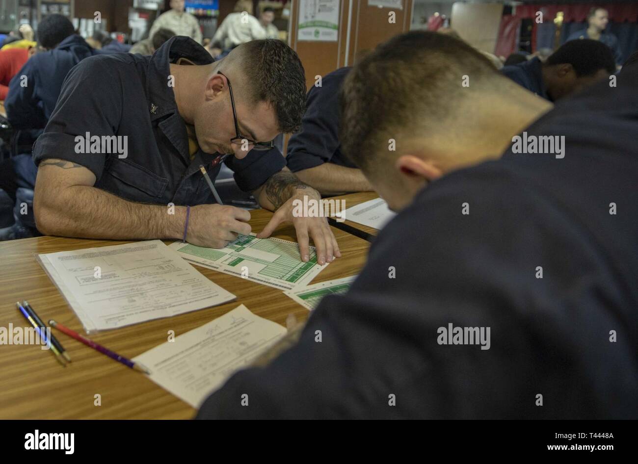 U.S. 5TH FLEET AREA OF OPERATIONS (March 14, 2019) Air Traffic Controlman 3rd Class Robert Wyker takes the Navywide petty officer second class advancement exam on the mess deck of the Wasp-class amphibious assault ship USS Kearsarge (LHD 3). Kearsarge is the flagship for the Kearsarge Amphibious Ready Group and, with the embarked 22nd Marine Expeditionary Unit, is deployed to the U.S. 5th Fleet area of operations in support of naval operations to ensure maritime stability and security in the Central Region, connecting the Mediterranean and the Pacific through the western Indian Ocean and three Stock Photo