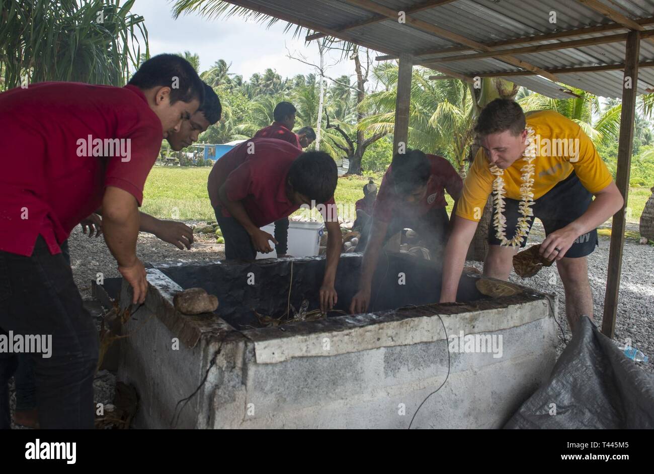 RONGRONG, Republic of the Marshall Islands (March 18, 2018) U.S. Navy Master-at-Arms 3rd Class Andrew Jones helps Marshallese students at Rongrong Christian School smoke a pig during a host nation engagement during Pacific Partnership 2019. Pacific Partnership, now in its 14th iteration, is the largest annual multinational humanitarian assistance and disaster relief preparedness mission conducted in the Indo-Pacific. Each year, the mission team works collectively with host and partner nations to enhance regional interoperability and disaster response capabilities, increase stability and securi Stock Photo