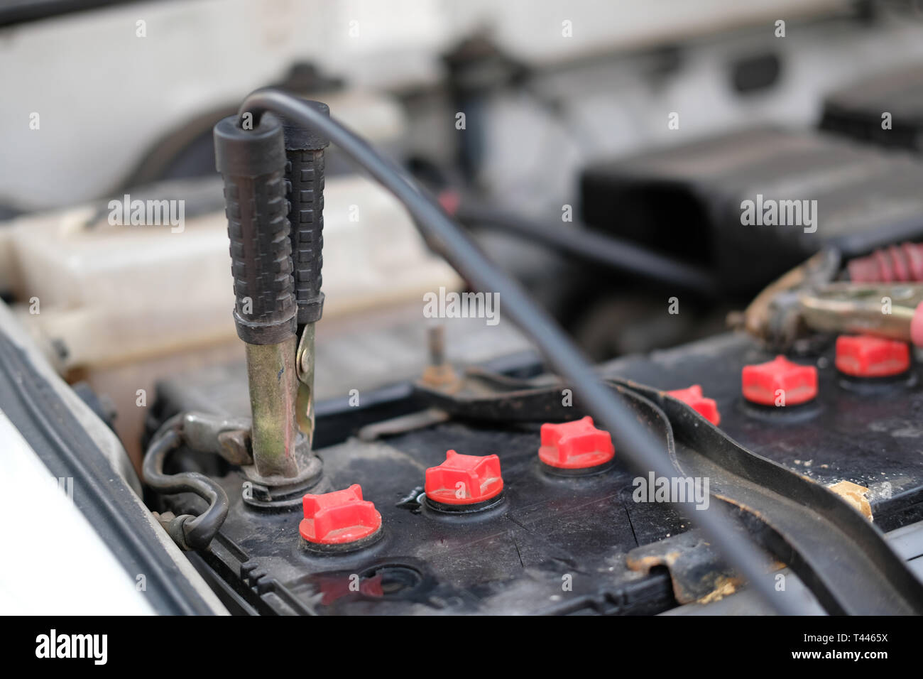 auto mechanic use jumper cables to charge dead car battery Stock
