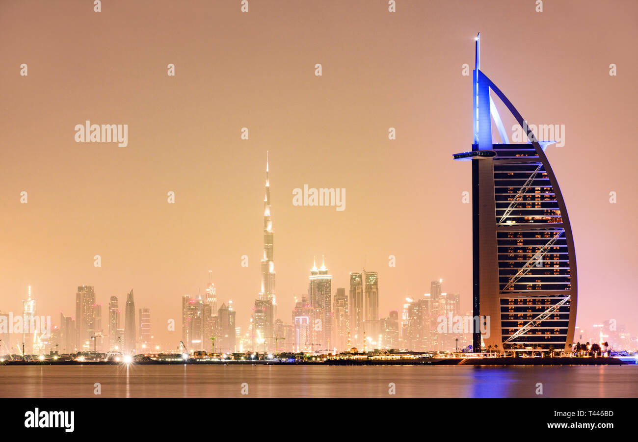 Stunning view of the illuminated Dubai skyline during sunset with the magnificent Burj Khalifa in the background and a luxury hotel in the foreground. Stock Photo
