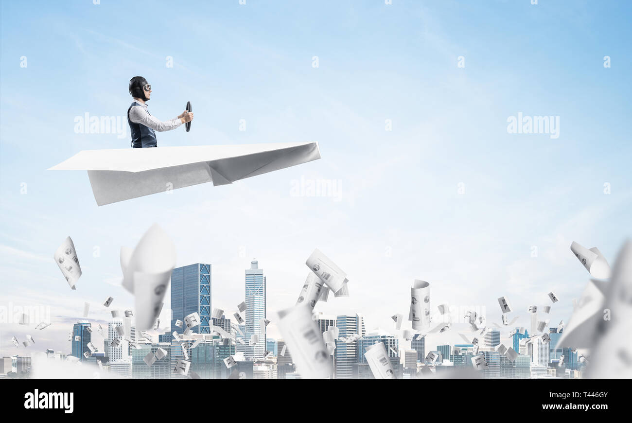 Businessman driving paper plane above business center in cloudy blue ...