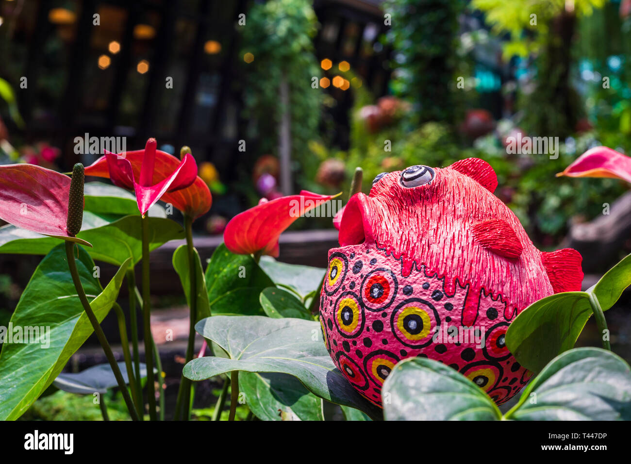 Cute colorful fish statue and Red anthurium flowes ( tailflower, flamingo flower, laceleaf ) decoration in the garden Stock Photo