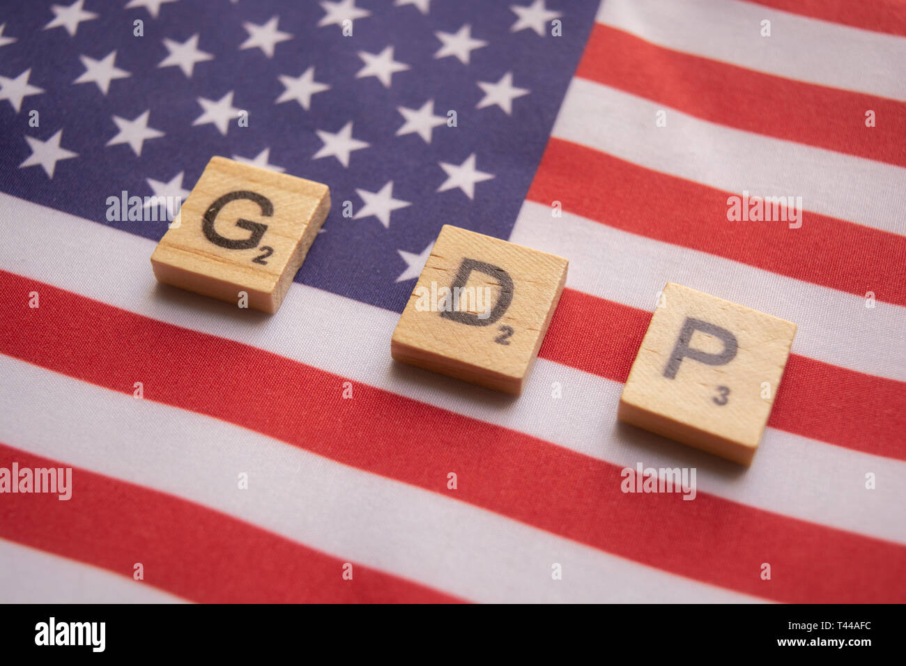 Finance Concept, GDP or Gross domestic product wooden block letters on US Dollar flag. Stock Photo