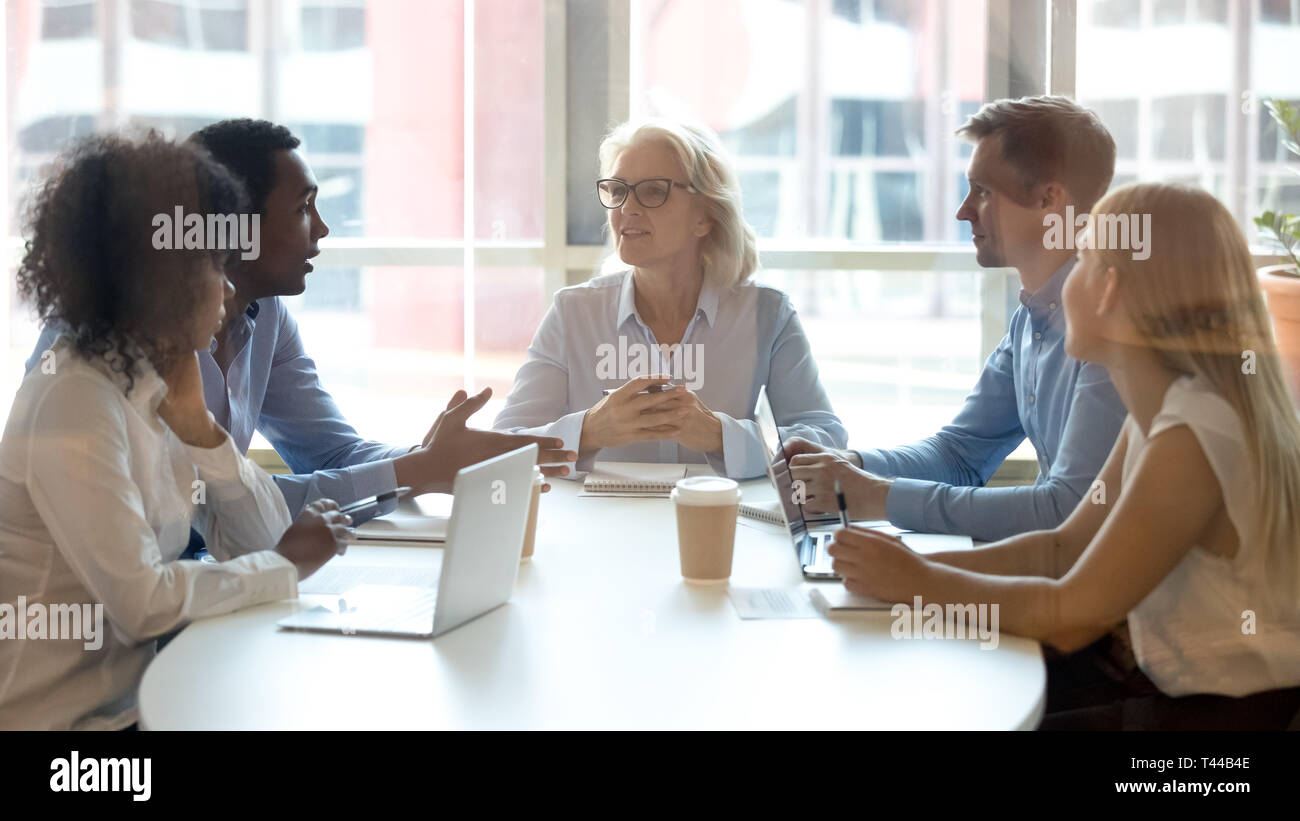 Multicultural professional team colleagues having conversation sit at conference table Stock Photo
