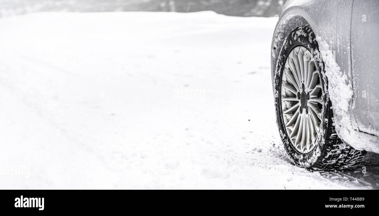 Detail of car winter tire - snow covered road, wide banner, empty space for text left. all logos brands on tyre removed  Stock Photo