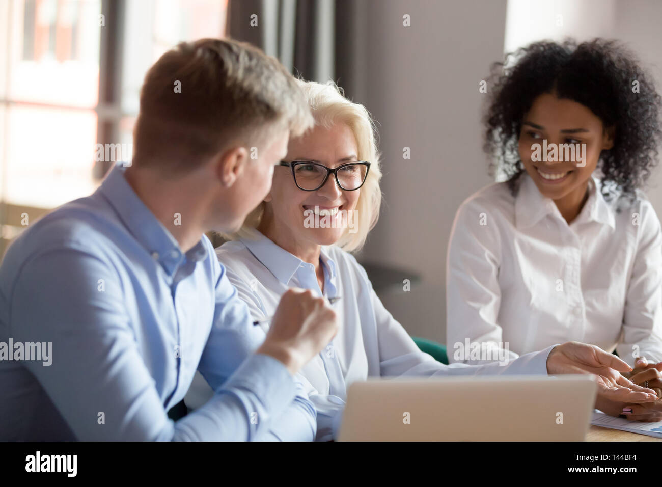 Smiling mature female mentor executive talking at diverse group meeting Stock Photo