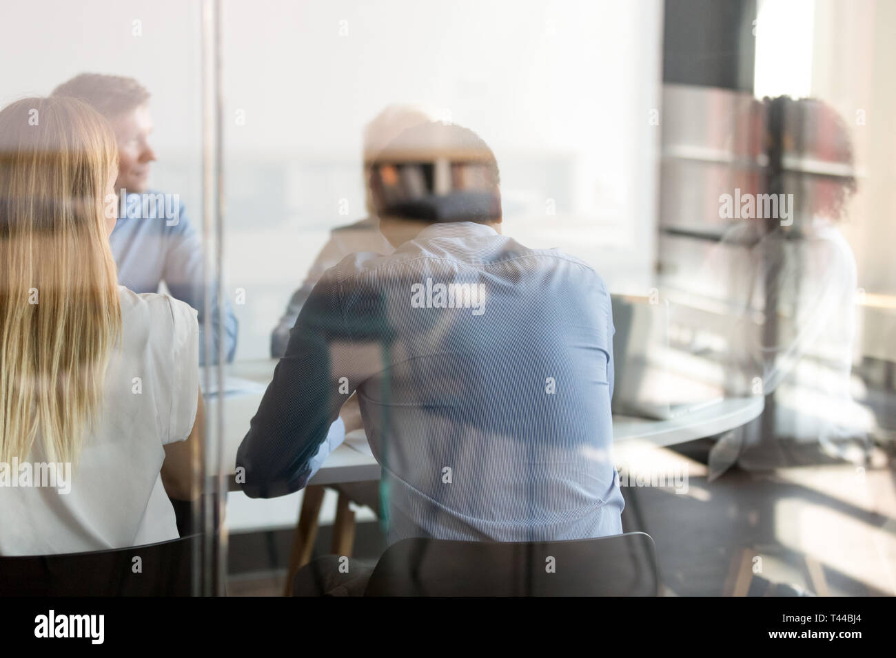 Multi ethnic business people negotiating at table view through glass Stock Photo