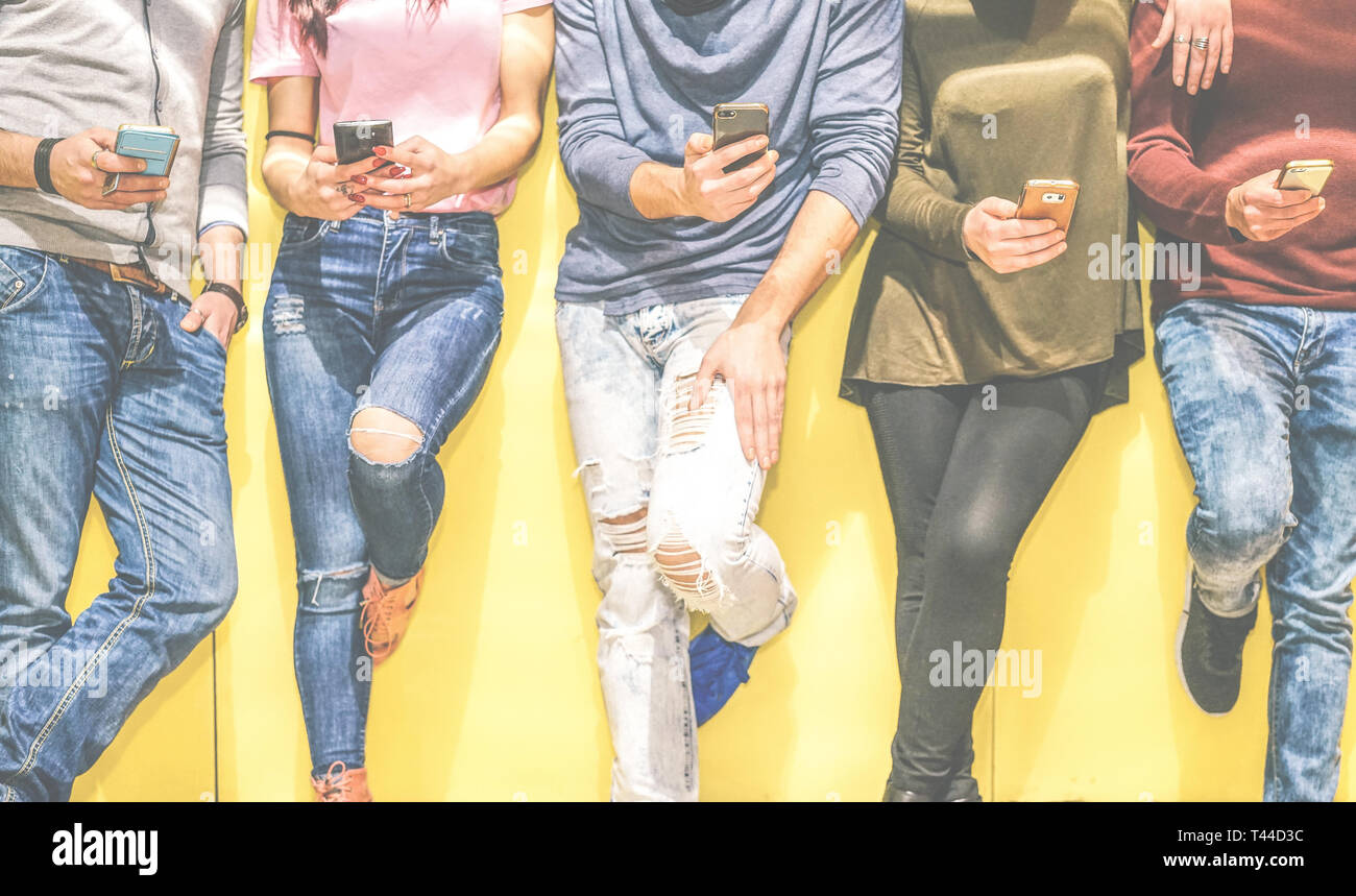 Group of young friends leaning on a wall using mobile phones - Multiracial people connecting on social network with smart phone Stock Photo