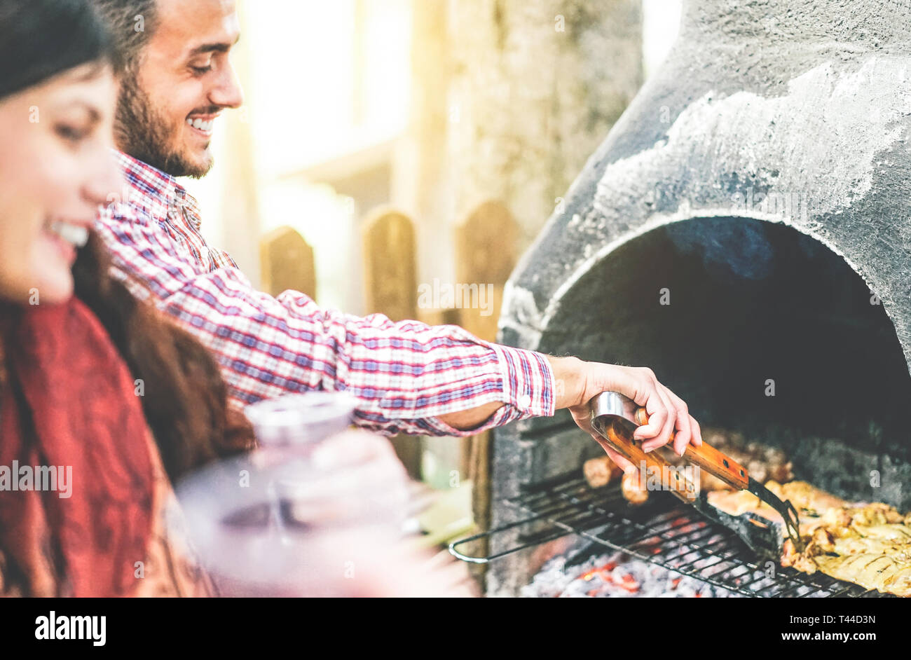 Happy young friends making a barbecue party grilling meat in the