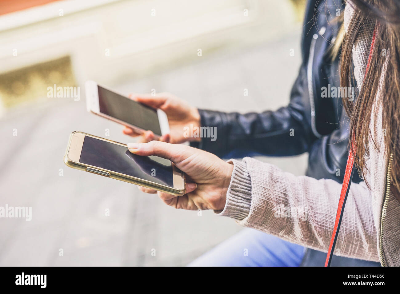 Close up of young women hands using mobile smart phones sitting in the city outdoor - New people addiction to electronic devices Stock Photo