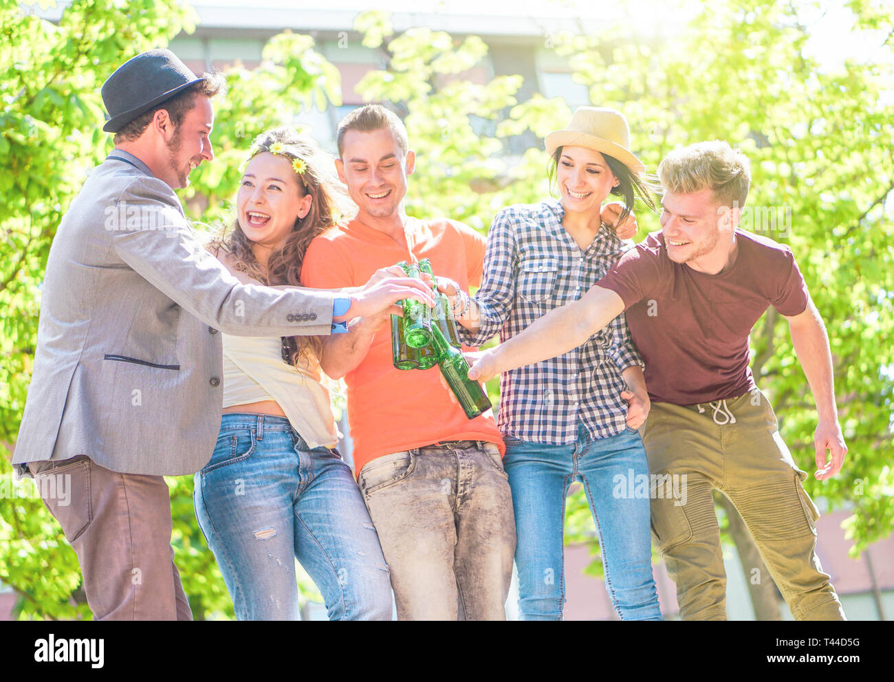 Group of friends enjoying beers outdoor - Happy young people having fun together toasting bottles of beer in the city - Youth friendship party concept Stock Photo