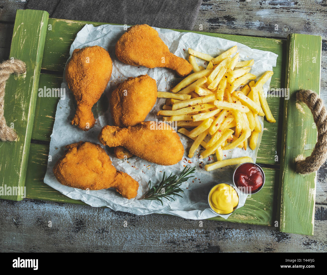 crispy fried chicken legs breaded golden color, french fries, sauce, wooden background Stock Photo
