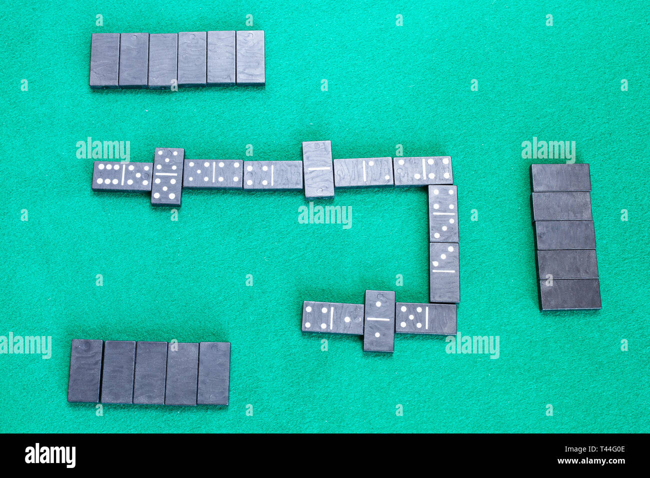 top view of playfield of dominoes board game with black tiles on green ...