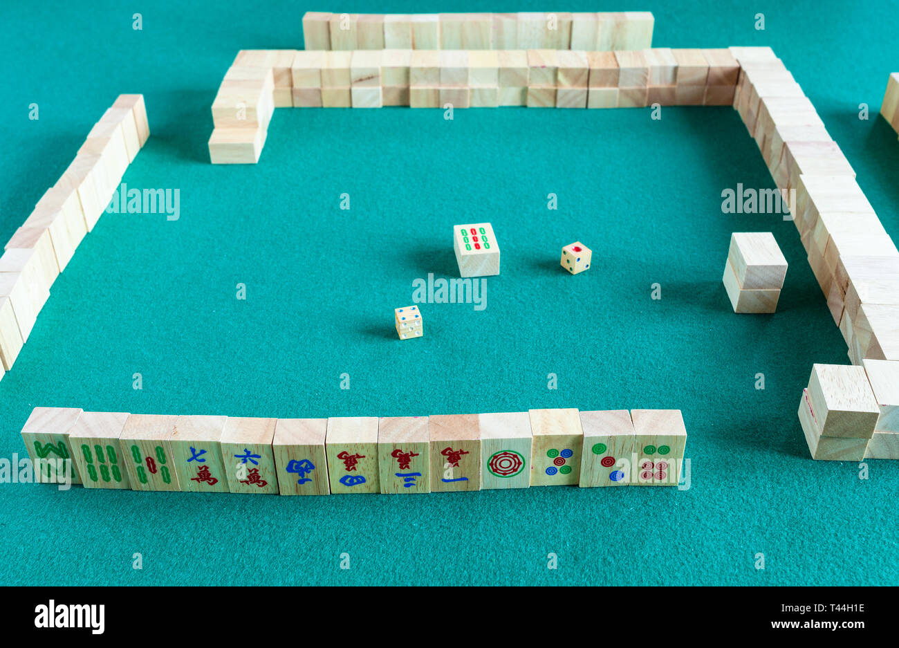 player's set at the beginning of mahjong game , tile-based chinese strategy board game on green baize table Stock Photo