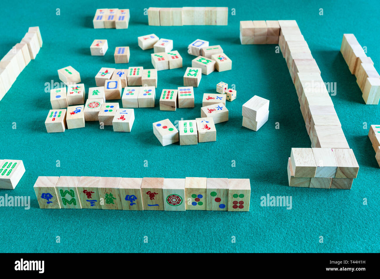 playing in mahjong game, tile-based chinese strategy board game on green baize table Stock Photo