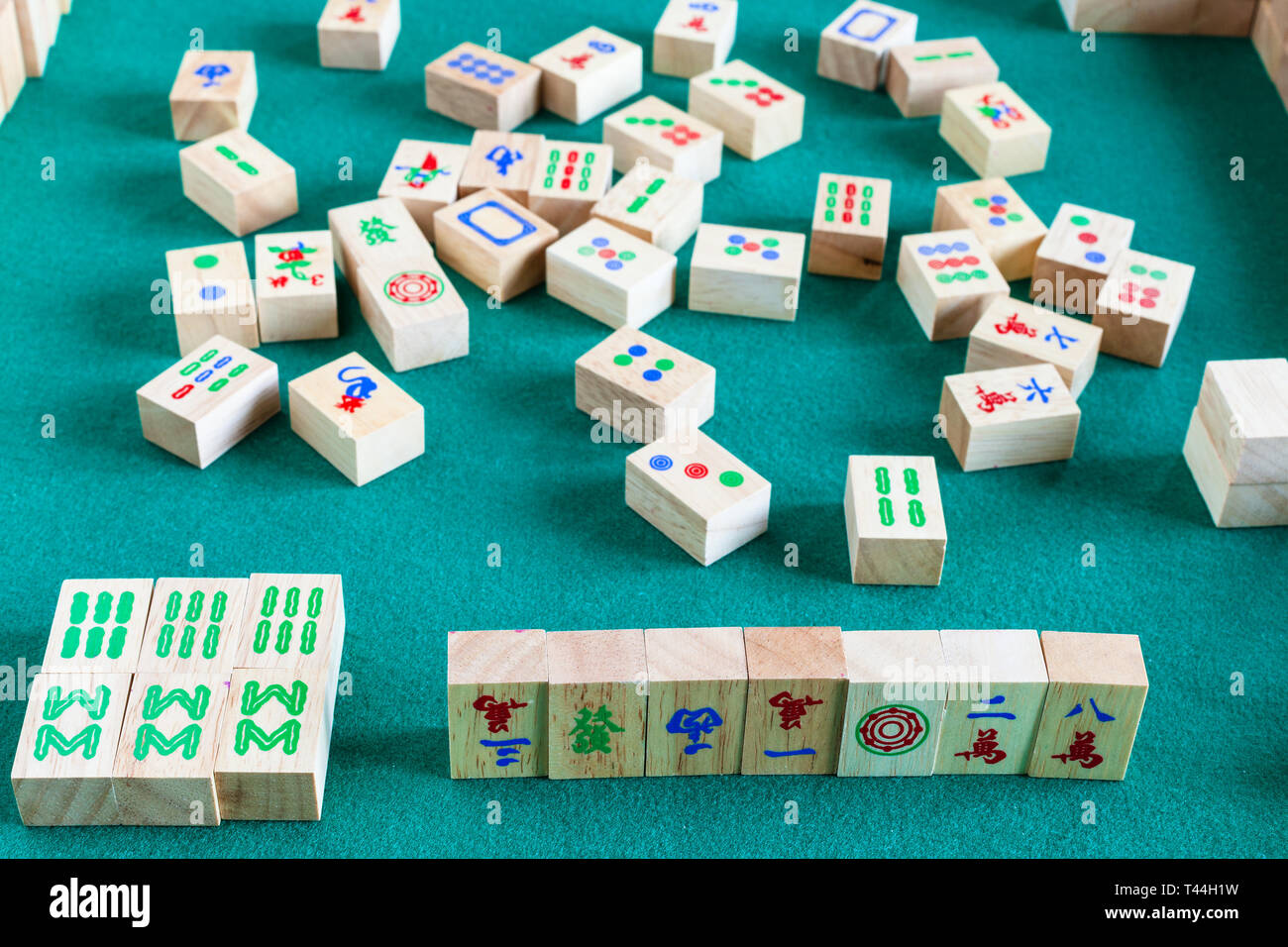 gameplay of mahjong game, tile-based chinese strategy board game on green baize table Stock Photo
