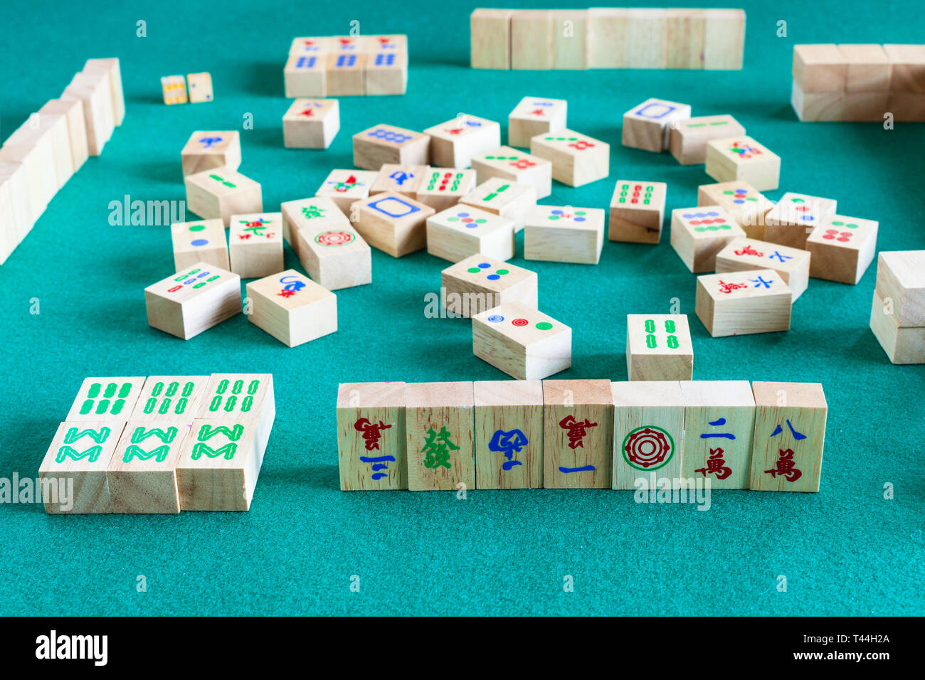 side view of gameboard of mahjong game, tile-based chinese strategy board game on green baize table Stock Photo