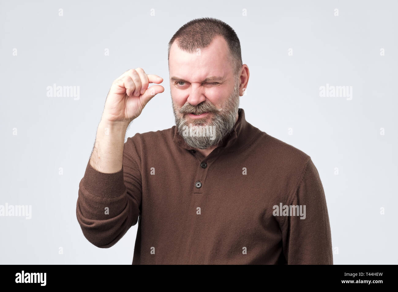 Mature caucasian man gesturing with hand showing small size Stock Photo