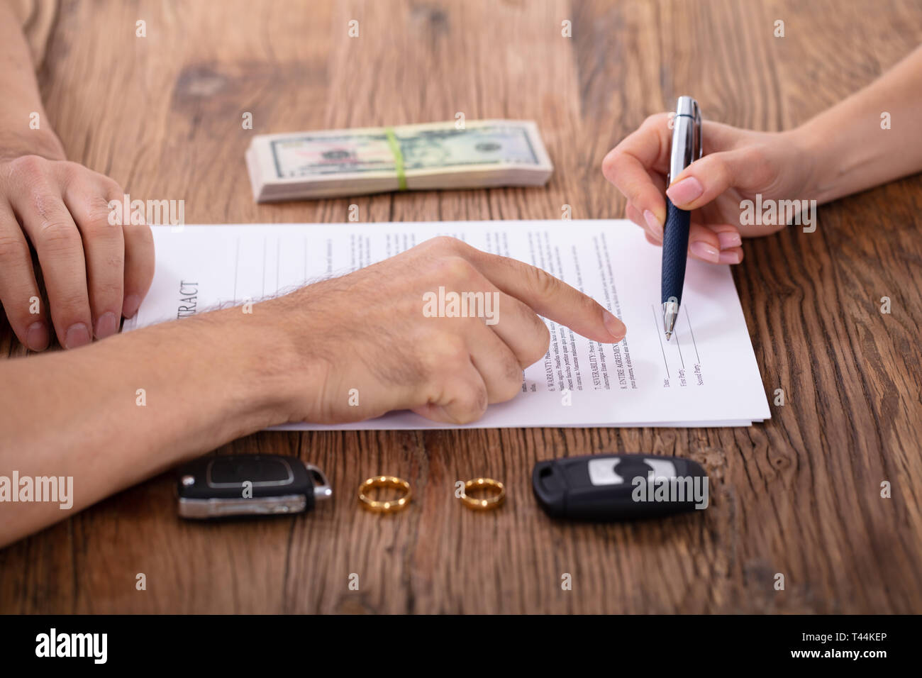 Judge Assisting Client In Filling Contract Form With Pair Of Golden Rings Stock Photo