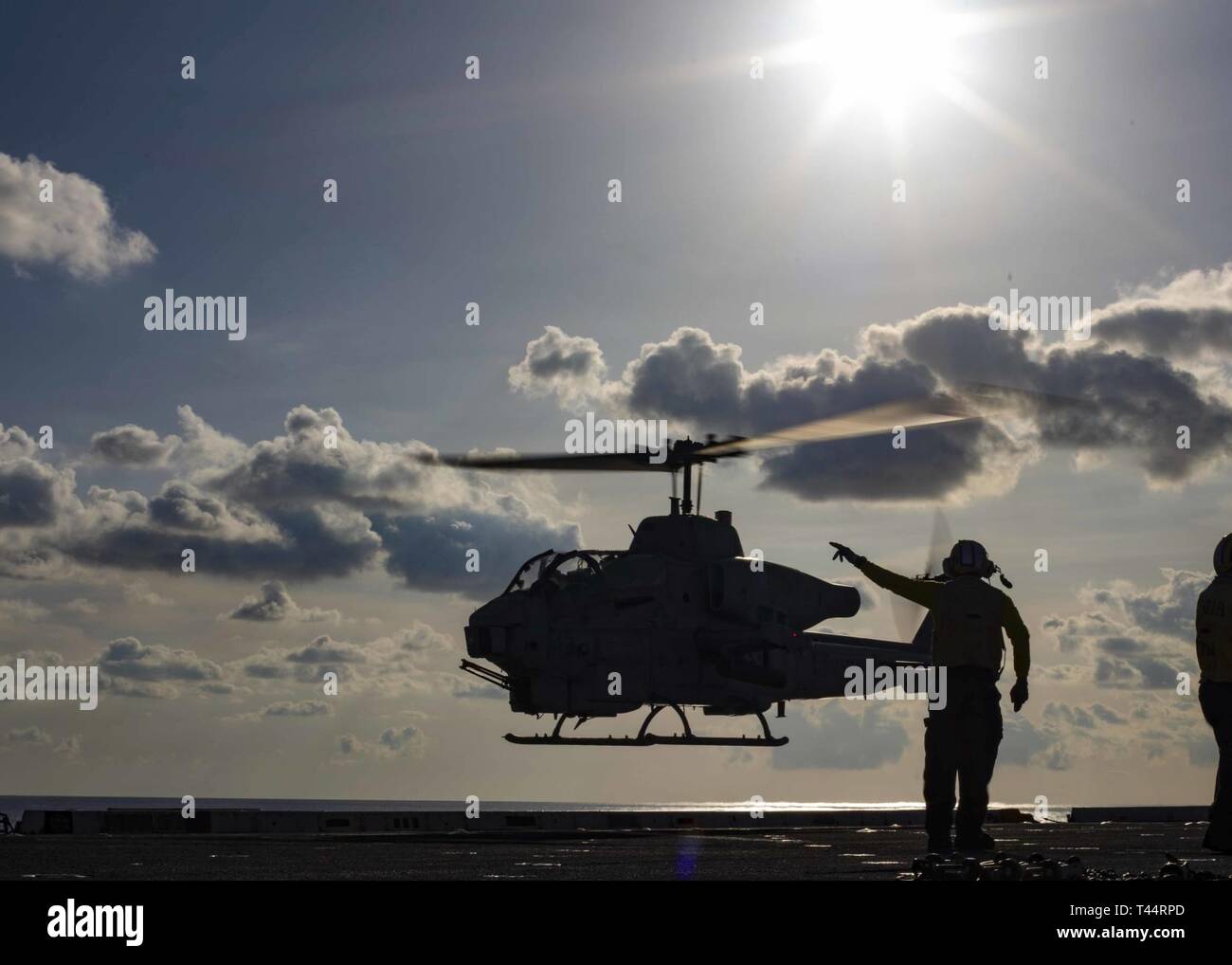 MEDITERRANEAN SEA (Feb. 21, 2019) Aviation Boatswain’s Mate (Handling) 3rd Class Devin Lewis signals to an AH-1W Super Cobra helicopter assigned to the “Black Knights” of Marine Medium Tiltrotor Squadron (VMM) 264 (Reinforced) to depart the flight deck of the San Antonio-class amphibious transport dock ship USS Arlington (LPD 24), Feb. 21, 2019. Arlington is on a scheduled deployment as part of the Kearsarge Amphibious Ready Group in support of maritime security operations, crisis response and theater security cooperation, while also providing a forward naval presence. Stock Photo
