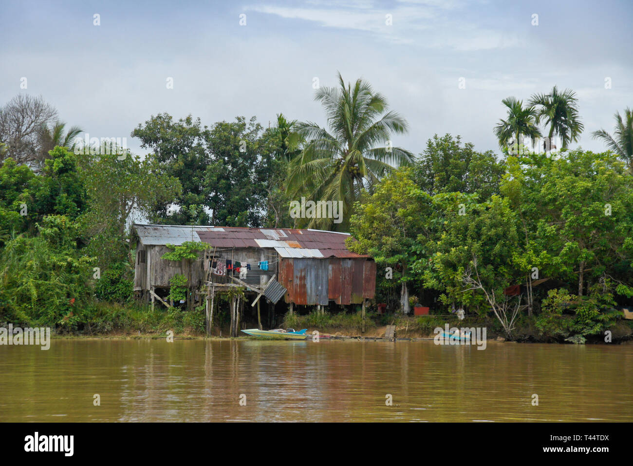 House on stilts and boat on bank of Kinabatangan River (Sungai