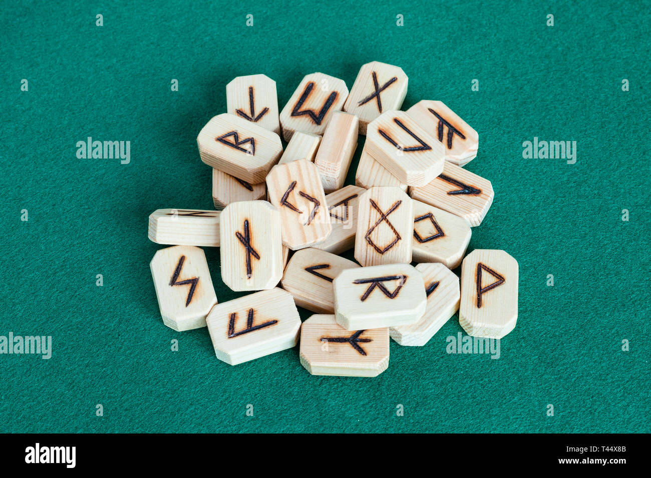 MOSCOW, RUSSIA - APRIL 3, 2019: pile of wooden tiles with fortunetelling runes on green baize table. Runes are the letters in various ancient Germanic Stock Photo