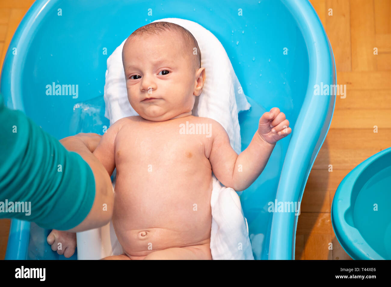 Mother bathing and washing baby in the plastic bathtub. Baby hygiene