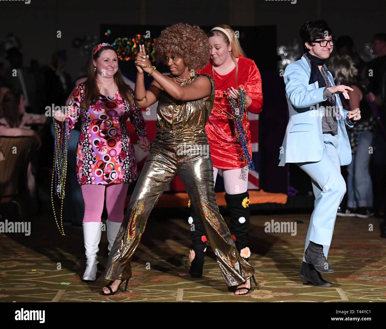 Members of the 81st Medical Operations Squadron portray the Austin Powers cast as they make their way down the aisle during the 31st Annual Krewe of Medics Mardi Gras Ball at the Bay Breeze Event Center on Keesler Air Force Base, Mississippi, Feb. 23, 2019. The Krewe of Medics hosts a yearly ball to give Keesler Medical Center personnel a taste of the Gulf Coast and an opportunity to experience a traditional Mardi Gras, which is celebrated by the local communities. The theme for this year's ball was Hollywood vs. Broadway. Stock Photo