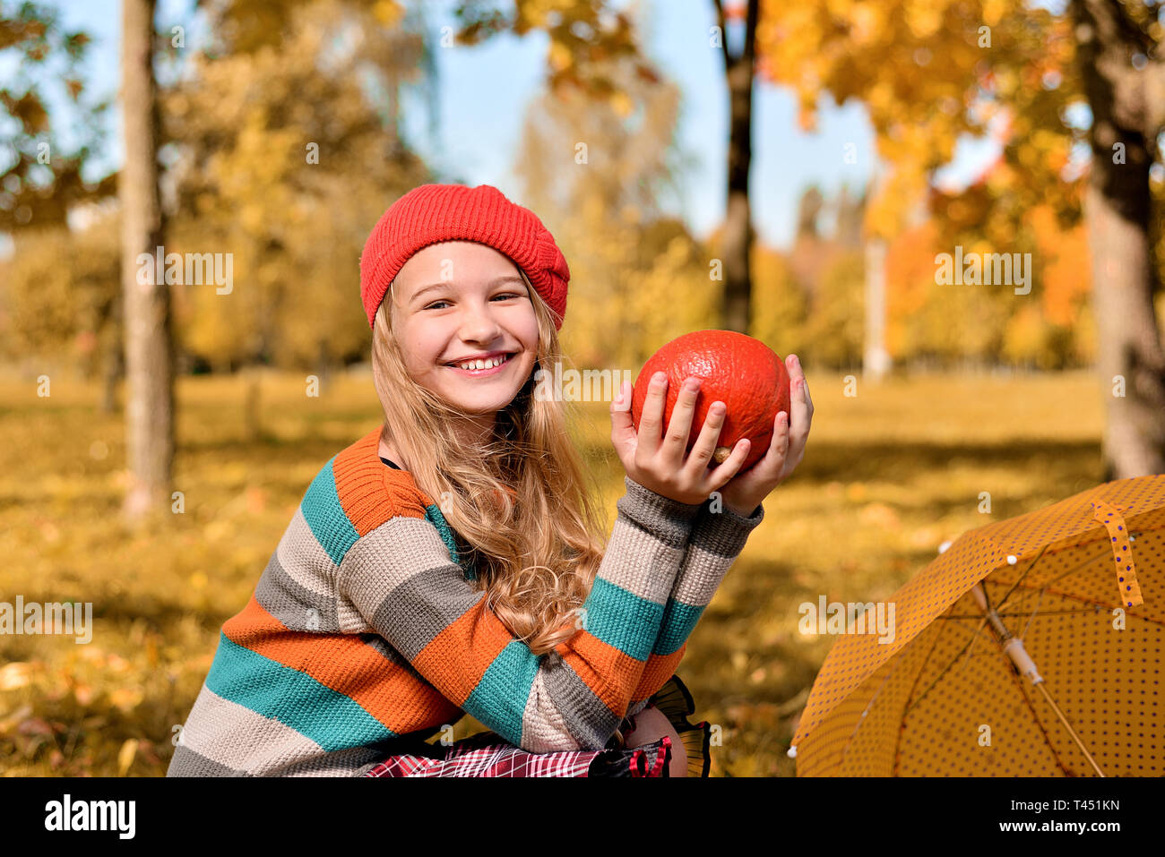 Autumn portrait of happy girl in red hat and sweater. teenager holds an ...
