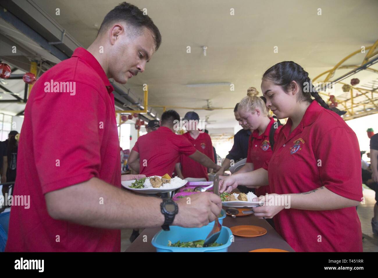 Cpl. John Robinson, a radio operator with Alpha Company, Battalion Landing Team, 1st Battalion, 4th Marines, the “China Marines,” grabs a bite to eat during a community relations event at Sabah Cheshire Home and Services in Sabah, Malaysia, Feb. 26, 2019. During the visit, the Marines and Sailors helped clean and renovate the facility by painting, clearing overgrown vegetation, and organizing storage space. Robinson, a native of Lafayette, Louisiana, graduated from Comeaux High School in May 2013 before enlisting in August 2016. Alpha Company Marines are the small boat raid specialists for BLT Stock Photo