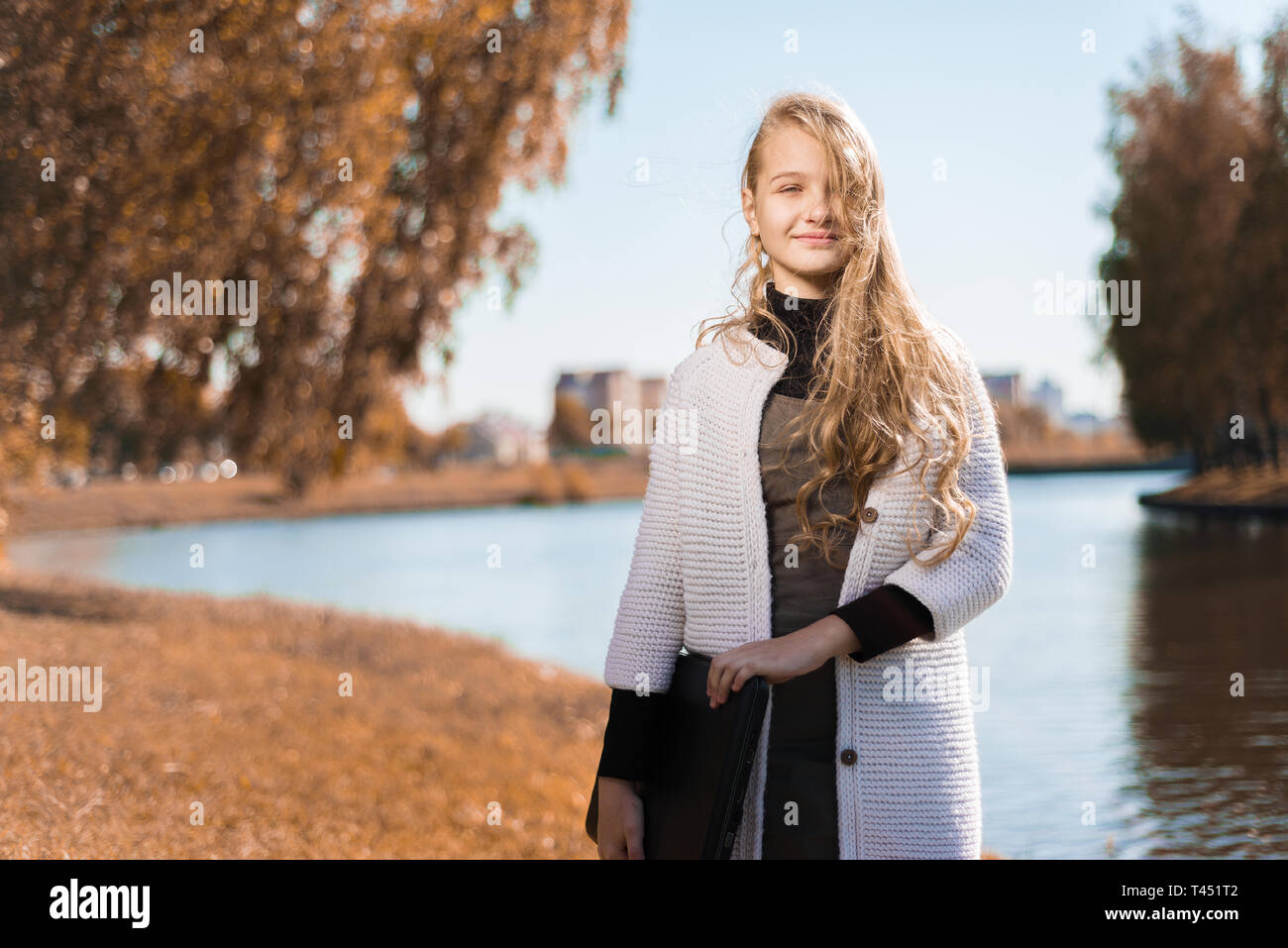 Portrait of beautiful young girl in school uniform. teenager holds laptop in nature near the lake Stock Photo