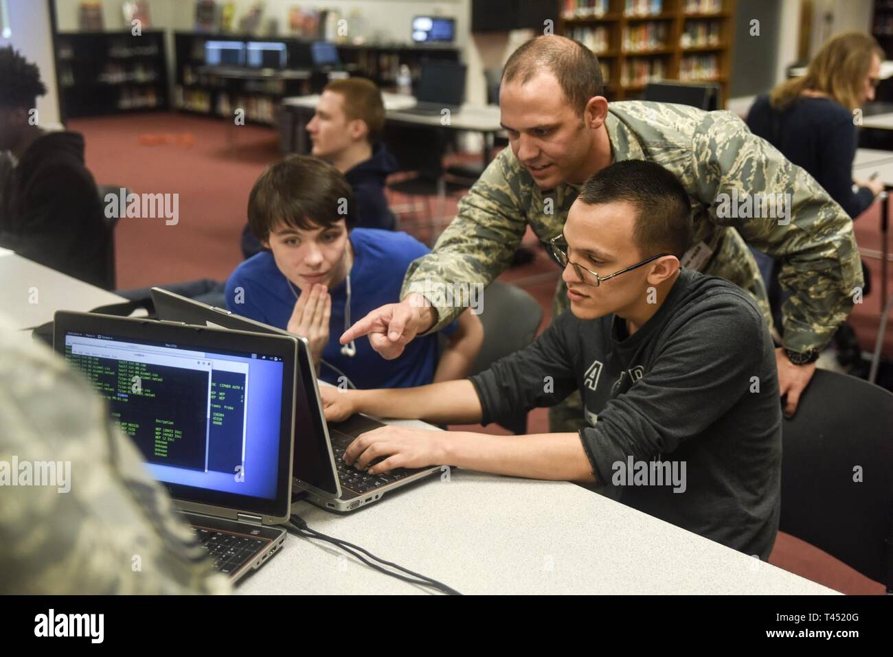 2nd Lt. Thomas Van Dorple, the 189th Operations Group Detachment 1 cyber operations flight commander, discusses a step in the computer science learning course with Stephen O'Rand and Chris Wright, Feb. 26, 2019, during a computer science class at Jacksonville Hight School, Jacksonville, Ark. The course was hosted by Mr. Sam Grubb, a cyber security education specialist and teacher at the high school who built the course to teach basic computer science skills with a foundation on security concepts. Stock Photo