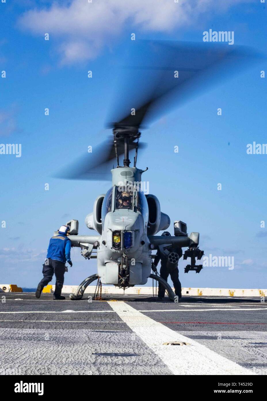 MEDITERRANEAN SEA (Feb. 26, 2019) Sailors remove chains on an AH-1W Super Cobra helicopter assigned to the “Black Knights” of Marine Medium Tiltrotor Squadron (VMM) 264 (Reinforced) on the flight deck of the San Antonio-class amphibious transport dock ship USS Arlington (LPD 24), Feb. 26, 2019. Arlington is on a scheduled deployment as part of the Kearsarge Amphibious Ready Group in support of maritime security operations, crisis response and theater security cooperation, while also providing a forward naval presence. Stock Photo