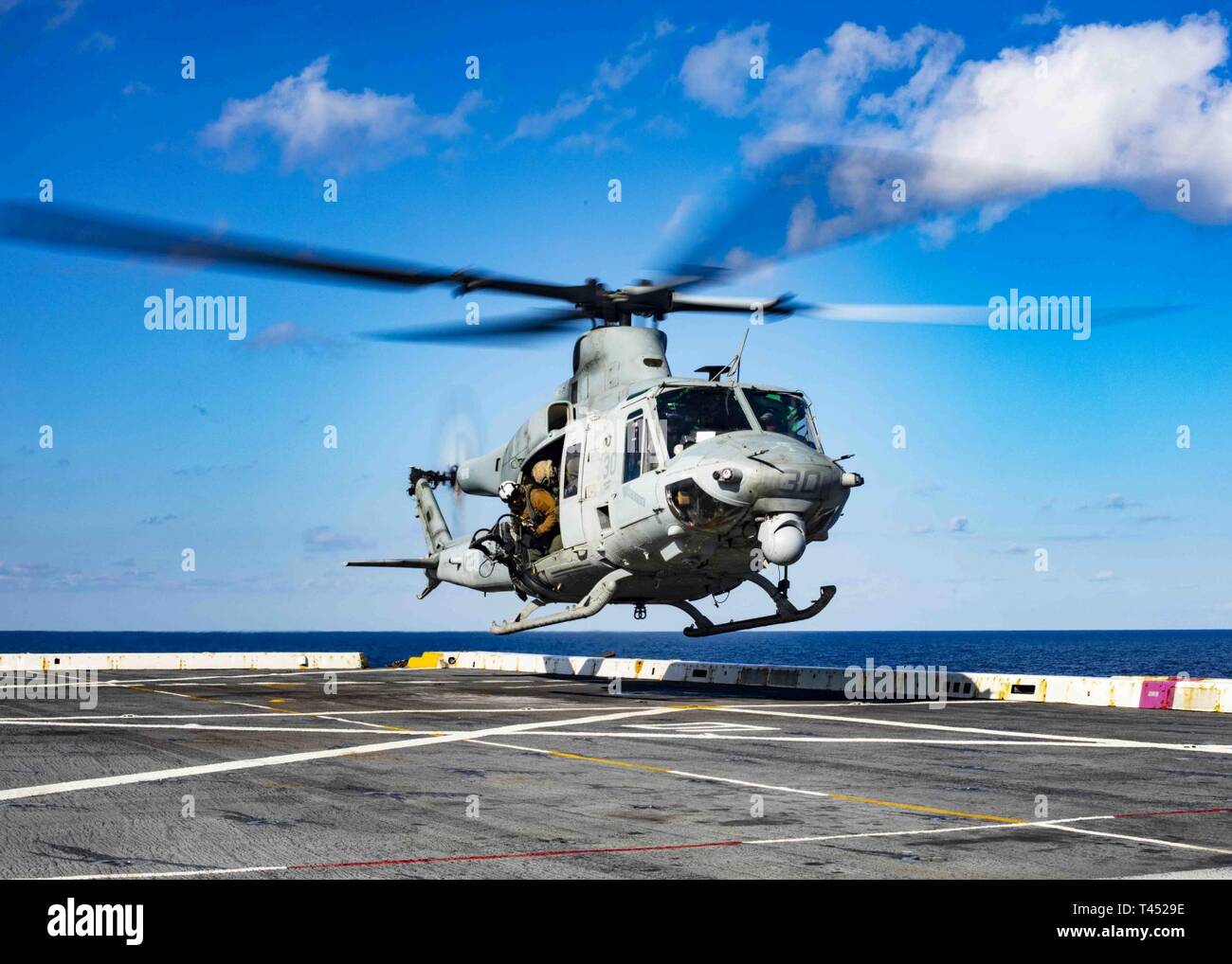 MEDITERRANEAN SEA (Feb. 26, 2019) A UH-1Y Huey helicopter assigned to the “Black Knights” of Marine Medium Tiltrotor Squadron (VMM) 264 (Reinforced) lands on the flight deck of the San Antonio-class amphibious transport dock ship USS Arlington (LPD 24), Feb. 26, 2019. Arlington is on a scheduled deployment as part of the Kearsarge Amphibious Ready Group in support of maritime security operations, crisis response and theater security cooperation, while also providing a forward naval presence. Stock Photo