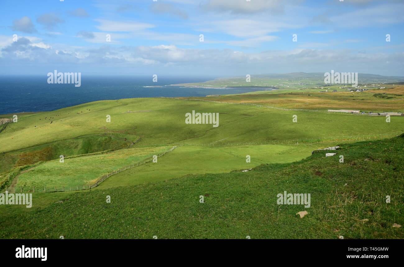 Irish landscape with grassland, a blue sky and some clouds. Some houses in the distance. Stock Photo