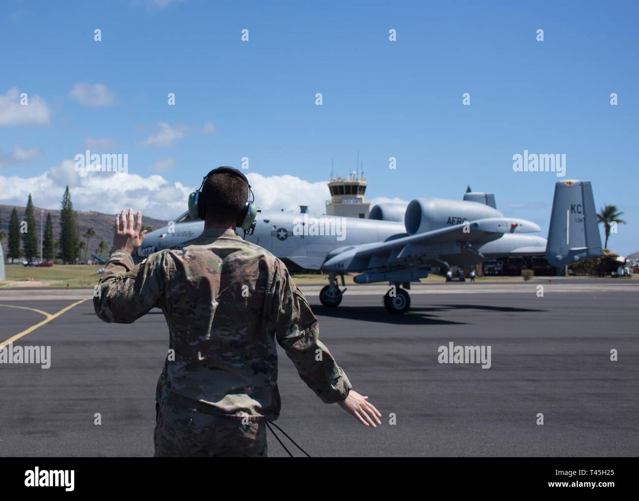 U.S. Air Force Tech. Sgt. Nick Schultz, crew chief with the 442d Aircraft Maintenance Squdron, marshalls an A-10 Thunderbolt II to perform Forward Arming and Refueling Point training at Pacific Missile Range Facility, Hawaii, Feb. 25, 2019. The FARP allows aircraft to hot refuel and reload enabling pilots to accomplish more missions in less time at austere locations. Stock Photo