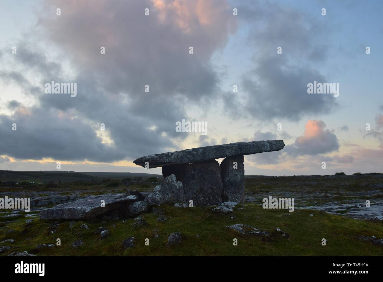 The stone tomb Poulnabrone or Poulnabrone dolmen in the Burren, County Clare, in Ireland, against the evening sky. Stock Photo