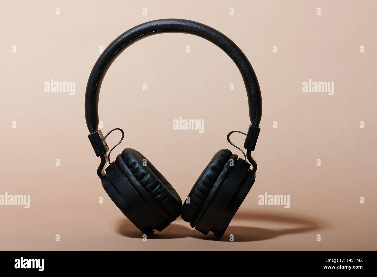 Front view of black headphones on beige color background Stock Photo