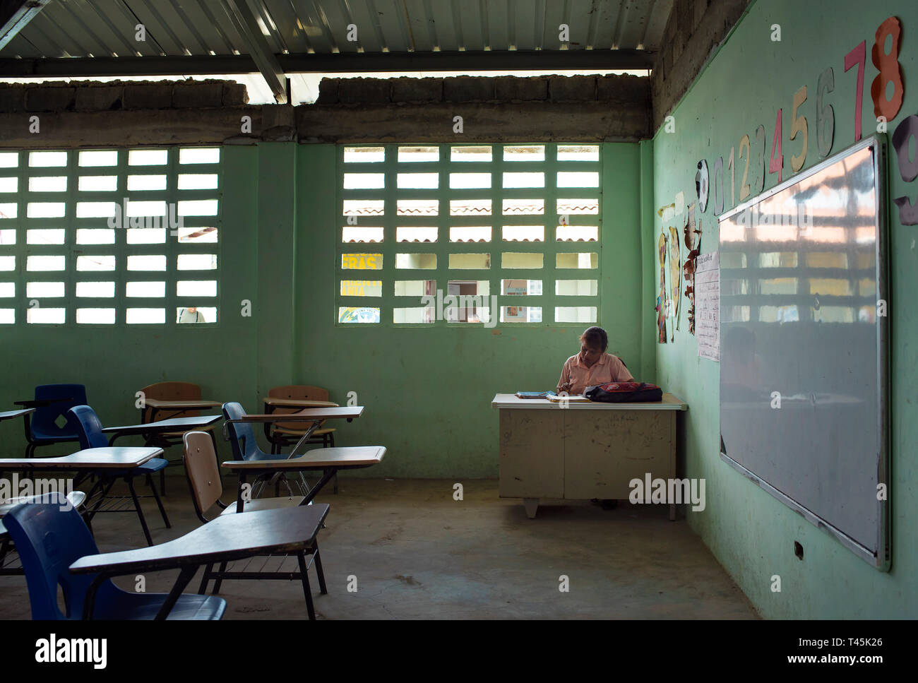 Occupied teacher working in the classroom after giving a class. Carti Sugdub; Guna Yala indigenous villages. San Blas Islands, Panama, Oct 2018 Stock Photo
