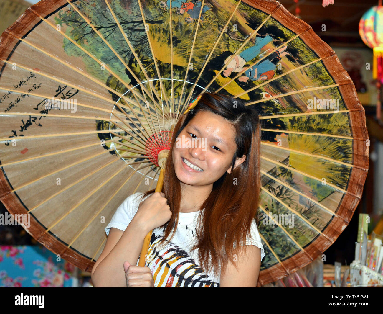 Smiling Taiwanese Hakka girl poses under a hand-painted traditional oil-paper parasol. Stock Photo